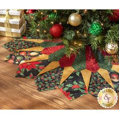 the christmas tree skirt is decorated with red, green and gold ribbon ornaments on it