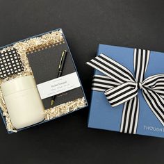 a gift box with a candle, notepad and pen