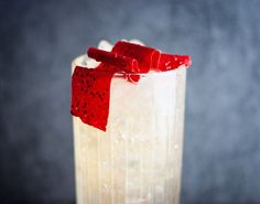 a drink with a red bow on the top is sitting in a tall glass filled with ice