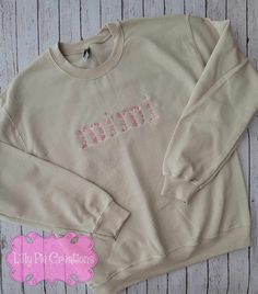 Stay cozy and look fabulous with this custom floral word embroidered sweatshirt. For words up to 5 letters to make a statement that's cute and unique! Choose from pink, blue or neutral colors, all on a beige sweatshirt for a chic look. Get ready to rock your new style! All of my items are made to order, if you have any questions please don't hesitate to ask! Pink Sweatshirt With Embroidered Logo For Spring, Trendy Sweatshirt With Letter Embroidery For Spring, Cute Cream Cotton Sweatshirt, Trendy Tops With Custom Embroidery For Fall, Fall Fleece Tops With Letter Embroidery, Pink Trendy Sweatshirt With Embroidered Logo, Trendy Pink Sweatshirt With Embroidered Logo, Fall Sweatshirt For Loungewear With Embroidered Text, Cream Cotton Sweatshirt With Letter Embroidery