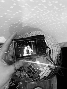 a person holding a cell phone in front of a disco ball