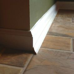 the corner of an empty room with tile flooring and green walls, in front of a doorway