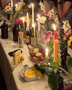 a group of people sitting around a table with food and candles