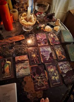 a table topped with lots of cards on top of a wooden table next to candles