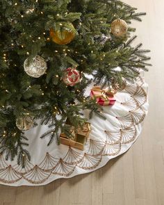 a christmas tree with presents under it on a white tablecloth and gold trimmings