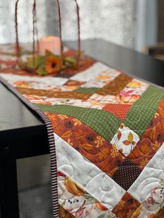 a quilted table runner with flowers and candles in the center on a dining room table