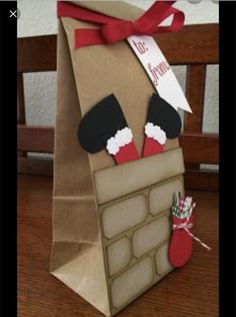 a brown paper bag with stockings and mittens on it sitting on a wooden table