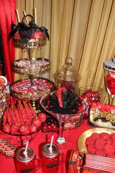 a table filled with candy and candies on top of red cloth covered tablescloth