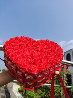 a heart shaped box filled with roses on top of a rail next to a building