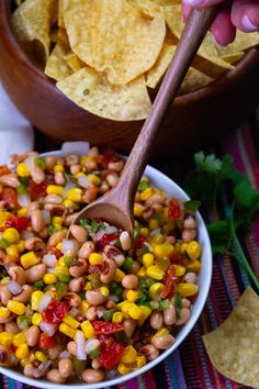 a bowl filled with beans and corn next to chips