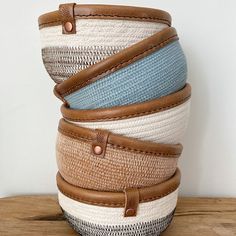 four baskets stacked on top of each other in different colors and sizes with leather handles