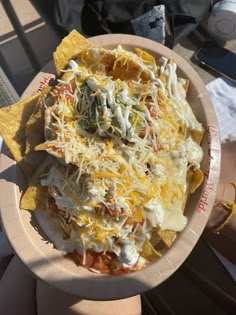 a paper plate filled with nachos and cheese