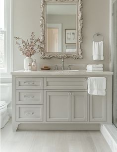 a white bathroom with a large mirror above the sink