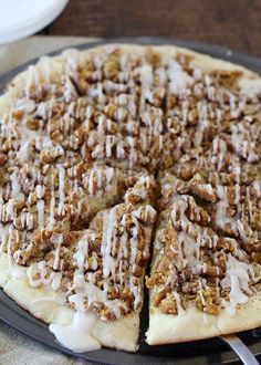 a close up of a pizza on a pan with white sauce drizzled over it