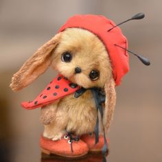 a small stuffed animal with a red hat and polka dot umbrella on it's head