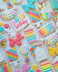 colorful decorated cookies are arranged on a white wooden surface with happy birthday written in the middle