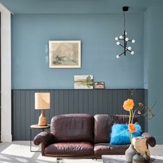 a living room with blue walls and brown leather couches in the corner, two lamps on either side