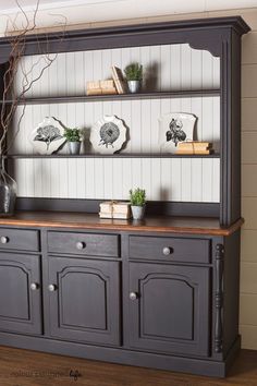 an old china cabinet painted in dark gray with white paneling and wood trimmings