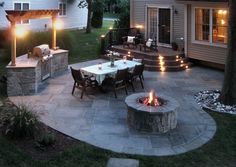 an outdoor patio with fire pit, seating and table lit up by lights at night