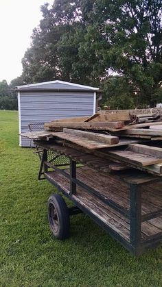 an old wooden cart with wood planks on the back and sides sitting in grass