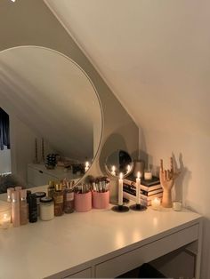 a mirror and some candles on a white counter in front of a wall mounted vanity