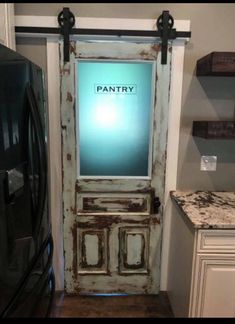 an old door with the word pantry painted on it in front of a black refrigerator