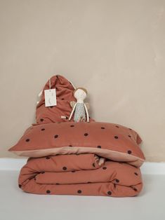 a stuffed animal sitting on top of a pile of pillows and blankets in front of a wall