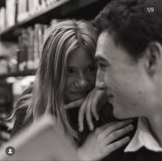 black and white photograph of a man and woman looking at each other in front of bookshelves