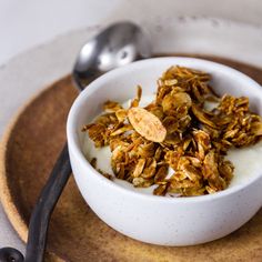 a white bowl filled with granola on top of a wooden plate