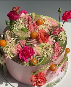 there is a cake with flowers on the top and sides that are pink, orange, and green