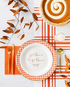 an orange and white place setting with goldware, napkins, and pumpkin decorations