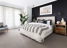 a bedroom with black walls and white bedding, two gray chairs and a large window