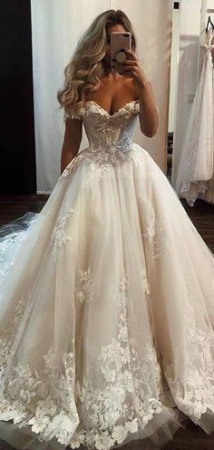 a woman taking a selfie while wearing a wedding dress in front of a mirror