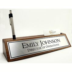 a wooden sign with a pen on it that says,'emly johnson director of operations '