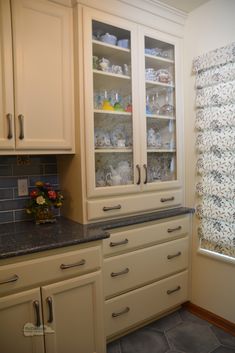 a kitchen with white cabinets and black counter tops in front of a glass doored window