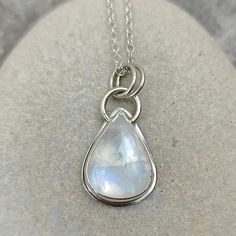 This elegant teardrop shaped Rainbow Moonstone has a fabulous blue flash across its surface when moved.  The stone is set in a Fine Silver bezel and sits on 0.7mm Sterling Silver sheet.  The top loop is made from 1.3mm round Sterling Silver wire and the two bail loops are made from 1mm Sterling Silver wire. The pendant including the bail loops measures 30.5mm x 16mm.   The back plate of the pendant measures 20.5mm x 16mm and the stone measures 18mm x 14mm. All measurements are approximate. The p Minimalist Teardrop Gemstone Jewelry, Blue Moonstone Teardrop Necklace, Silver Pear-shaped Moonstone Jewelry, Blue Teardrop Moonstone Jewelry, Teardrop Blue Moonstone Jewelry, Teardrop Moonstone Gemstone Necklace, Minimalist Teardrop Moon Charm Jewelry, Minimalist Teardrop Jewelry With Moon Charm, Teardrop Moonstone Necklace With Birthstone