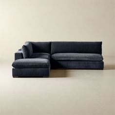 a blue sectional couch sitting on top of a wooden floor next to a white wall