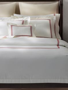 a bed with white sheets and red trimmings