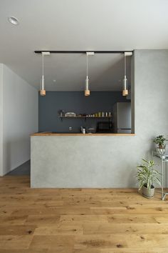 an empty kitchen with wooden floors and white walls, along with hanging lights above the counter