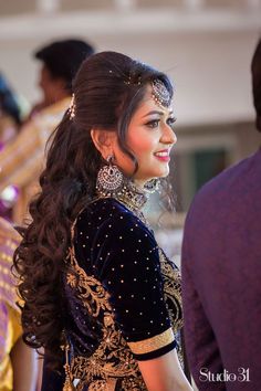 a woman with long hair wearing a black and gold outfit, standing in front of other people