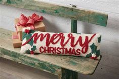 a christmas pillow sitting on top of a wooden bench next to a box with a bow