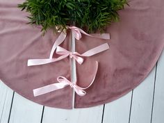 a round table with pink velvet and ribbon tied around the edge, on which is a potted plant