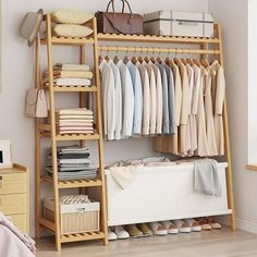 an organized closet with clothes, shoes and bags on shelves in front of a bed