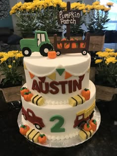 a three tiered cake decorated with pumpkins and trucks