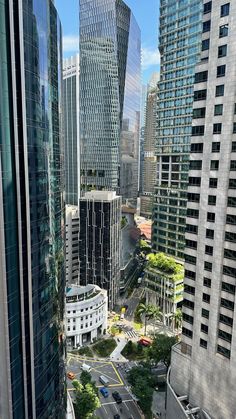 an aerial view of some very tall buildings in the city with cars driving down it