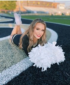 a woman laying on the ground with a cheerleader pom pom in her hand