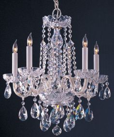 a crystal chandelier hanging from the ceiling with four candles in it and three lights on each side