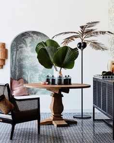 two chairs and a table in a room with plants on the wall behind them,