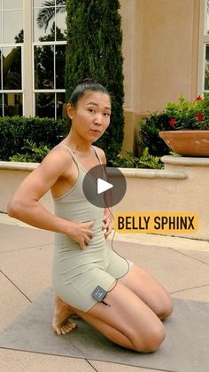 a woman sitting on top of a yoga mat in front of a building with the caption belly sphnk