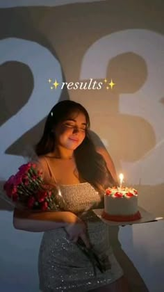 a woman holding a cake with candles on it and flowers in front of her face